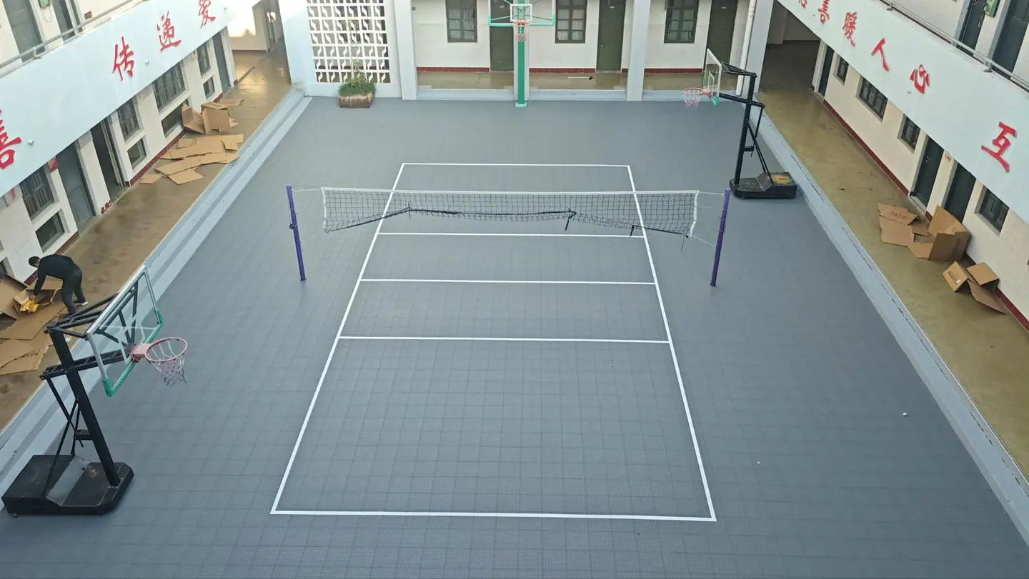 Grey courtyard volleyball surface with net and white markings