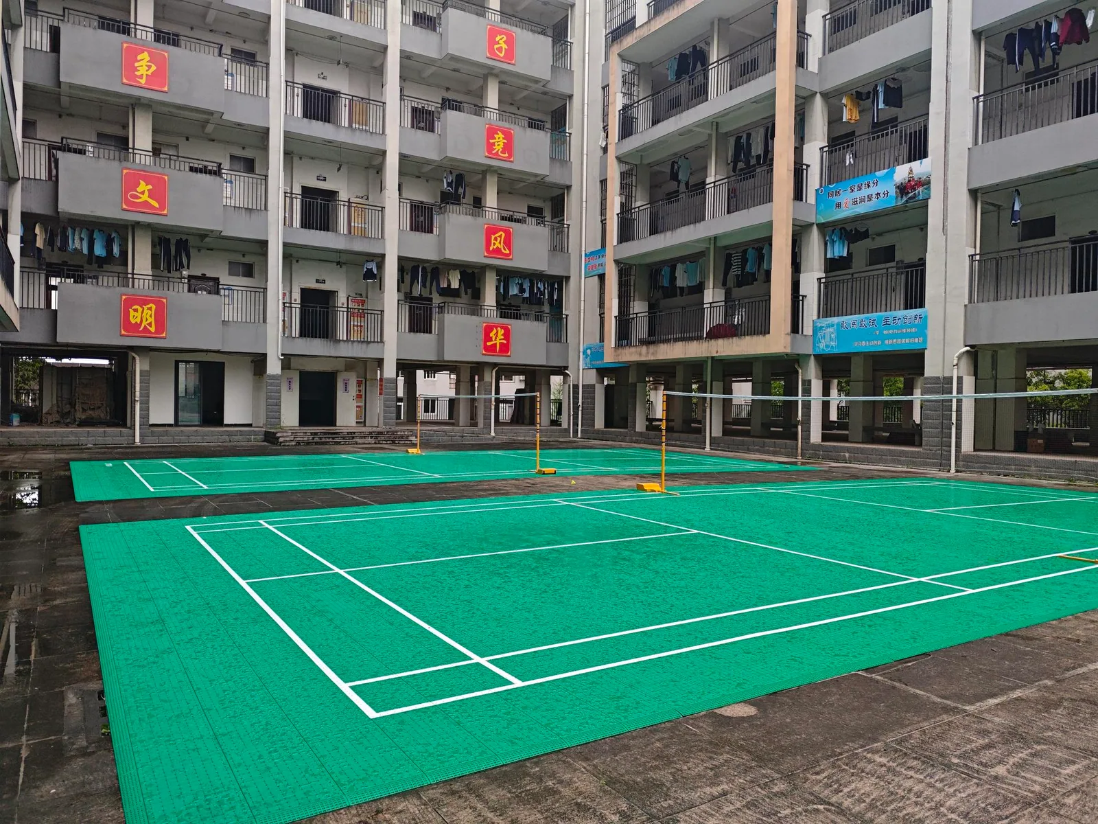 Green badminton court beside residential buildings