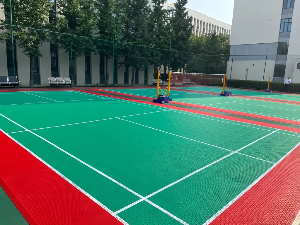 Green outdoor badminton court with red surrounds