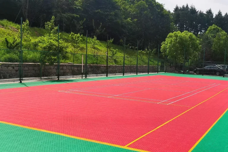 Red and green outdoor court surrounded by trees