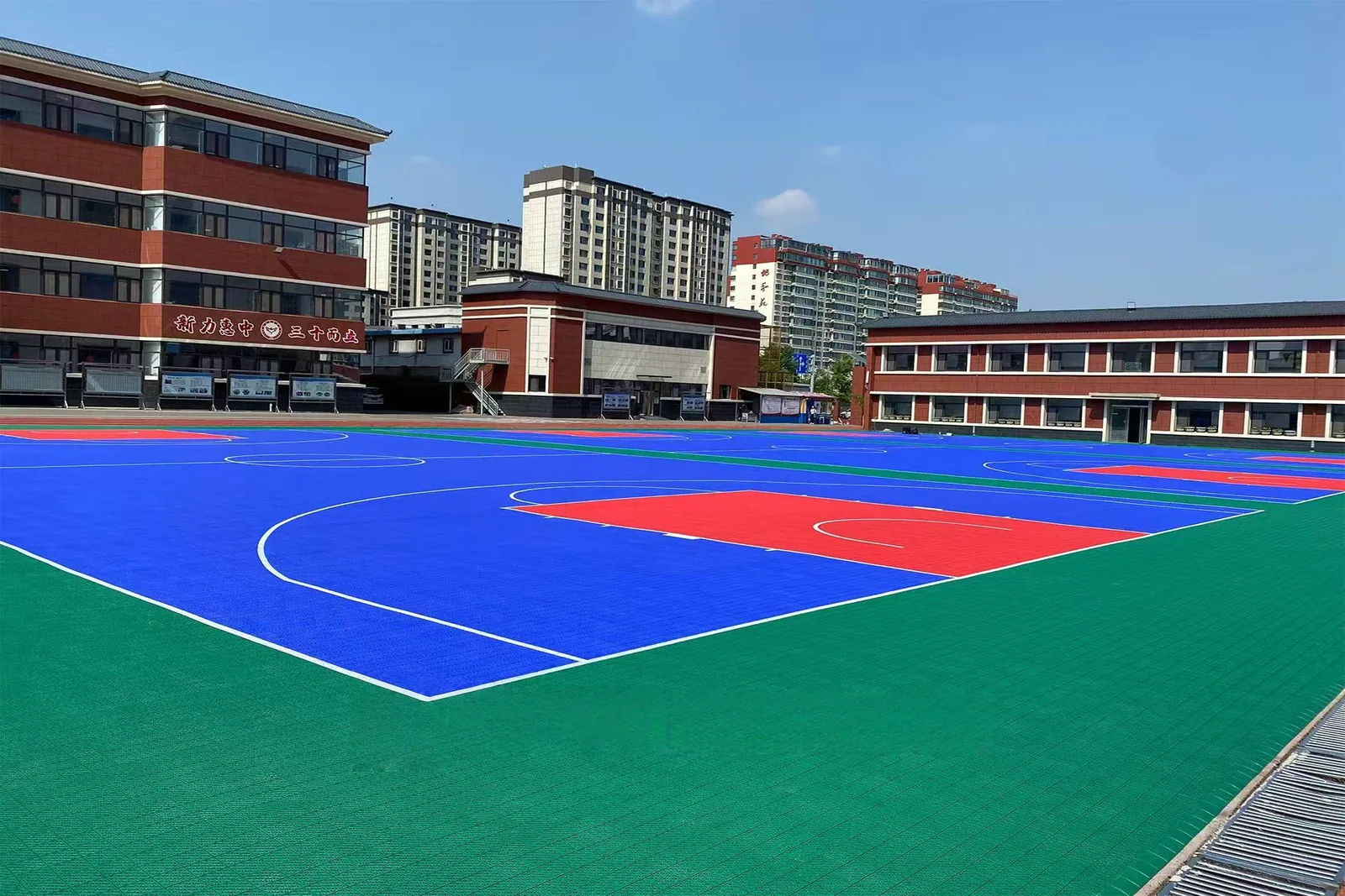 Blue and red basketball court beside school buildings