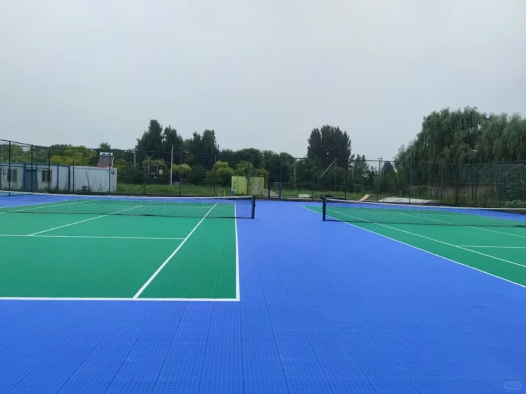 Outdoor tennis court with blue surrounds and green playing area